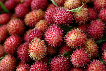 Obraz premium Rambutan fruit with vibrant hairy exterior displayed in a market setting during midday