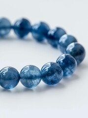 Close-up of glossy blue gemstone bracelet on white background.