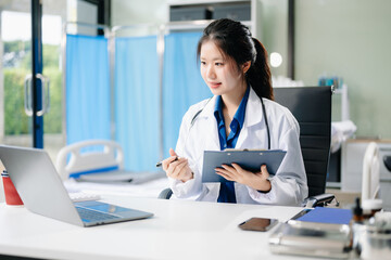 Confident young female doctor in white medical uniform sit at desk working on computer.