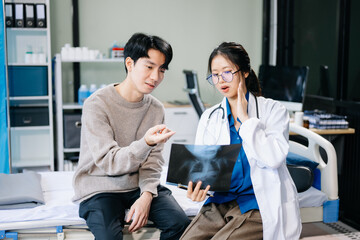 Fototapeta premium Doctor discussing treatment with male patient talks to discuss results or symptoms and sitting on examination desk