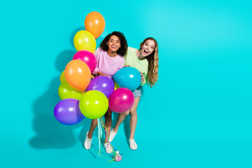 Vivid Scene of Two Diverse Joyful Women Posing with Colorful Balloons on Bright Turquoise Background