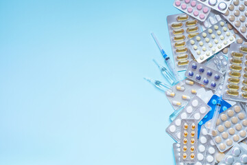 Assorted pharmaceutical blister packs and syringes on blue background