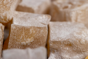 Turkish delight in with nuts , scattered oriental sweets Turkish delight with peanuts on a black board, close up, side view