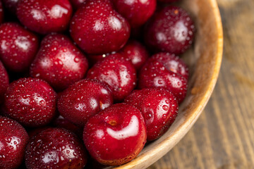 wet red cherry fruits on the kitchen table close up, berries in a wooden bowl