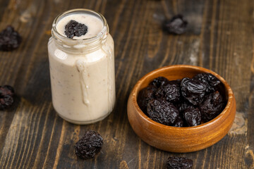 yogurt with prune with dried plum , glass jar with natural prune yogurt close up, side view
