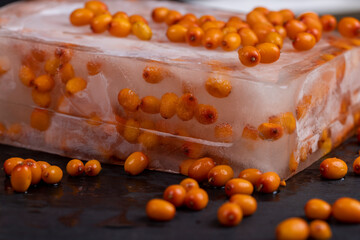 frozen sea buckthorn berries, ripe orange sea buckthorn berries during deep freezing, close up on black slate