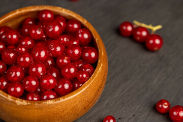 ripe currant berries poured in a wooden bowl, harvest small red currant berries on the kitchen table in a bowl, close up, side view