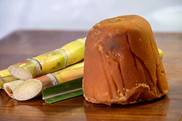 jaggery and sugar cane, which is a healthy sweetener and is of organic. a wooden background