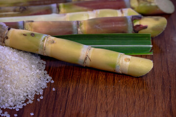 White sugar and sugar cane on wooden table background