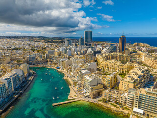 Drone aerial view of St. Julian's city, coast road, waterfront, buildings. Malta island