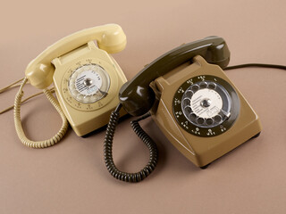 Vue aérienne de deux téléphones à cadran de couleur marron et beige avec câble et combiné, sur un fond ton sur ton.