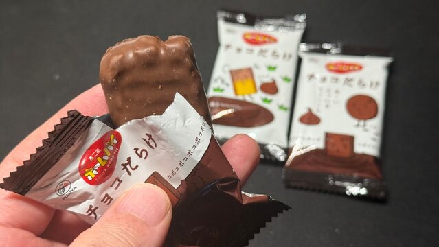 不二家ホームパイ「チョコだらけ」個包装のスナック菓子を手に持った写真｜人気のチョコレート菓子