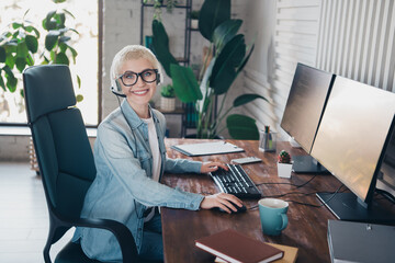 Young professional woman working remotely using two monitors in a modern home office setting