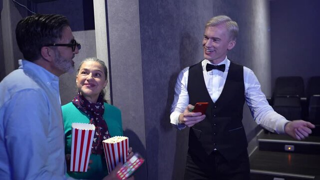 People entering cinema, getting tickets checked, and finding seats