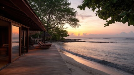 A wooden overwater bungalow at sunrise, with calm ocean waves lapping below.