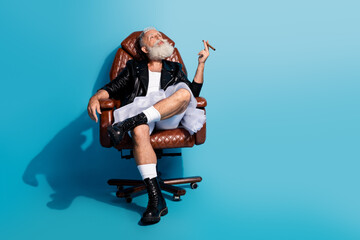 Photo of senior man sit chair smoke cigar wear skirt jacket isolated blue color background