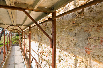 REMOVING OLD PLASTER FROM A STONE AND BRICK WALL - Construction work on a building site with...