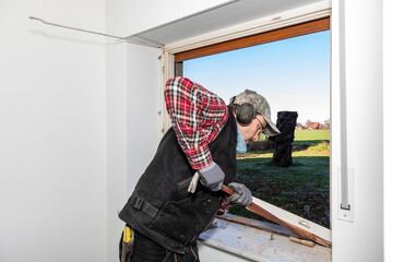 Carpenter removing old window frame during renovation.
