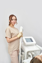 Female caucasian young adult medical professional in spa clinic holding laser hair removal device.