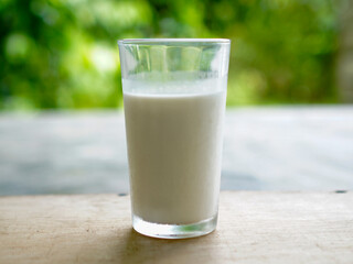 A clear glass filled with fresh milk stands on a bokeh background. Fresh milk for healthy life