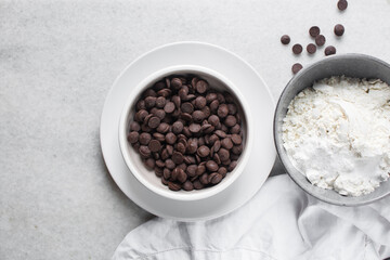 Overhead view of dark chocolate chips in a white bowl, top view of chocolate chips on a white background