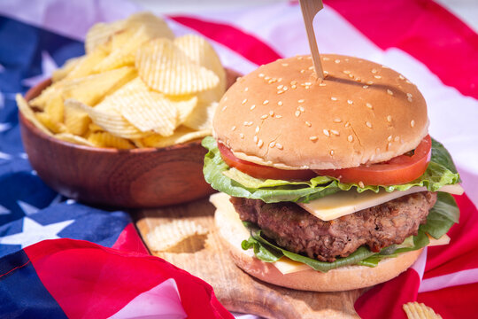 Tasty cheeseburger, chips and sauce with patriotic american flag