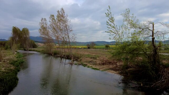 Calm river flows through green countryside under cloudy sky