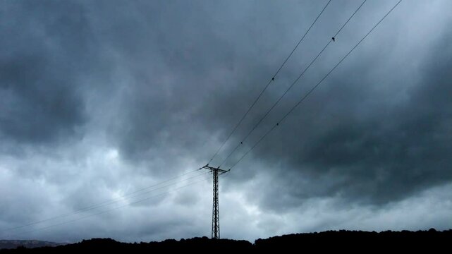 Ominous clouds moving above power lines and forest
