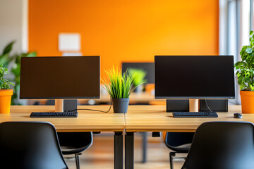 Fototapeta premium Modern Shared Workspace with Dual Monitors and Green Plants Against Orange Wall