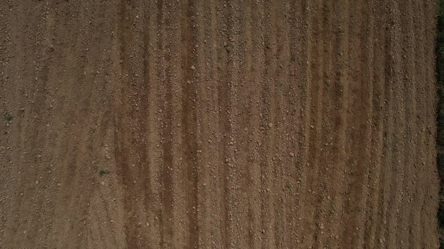 navigating across farmland, creating precise parallel lines while preparing soil for planting during seasonal cultivation from aerial perspective