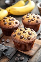 Delicious homemade chocolate chip muffins on wooden board with bananas for breakfast or snack food photography