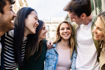 Group of cheerful young friends enjoying time together outdoors, embracing and smiling. Youth community and friendship concept