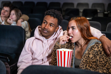 Young couple watching a movie and eating popcorn in a cinema