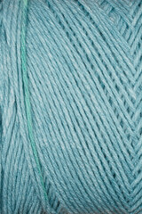 A close-up texture shot of blue yarn with diagonal stripes and a prominent green thread