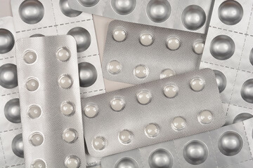 A detailed close-up of scattered blister packs with white round pills overlapping