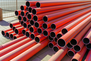 Stack of new, red, plastic, even, long pipelines. PE, HDPE tubes.