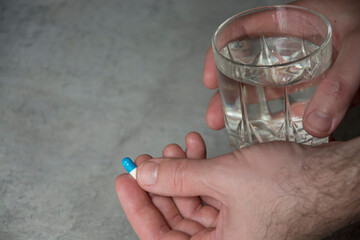 hand holding pill and a glass of water