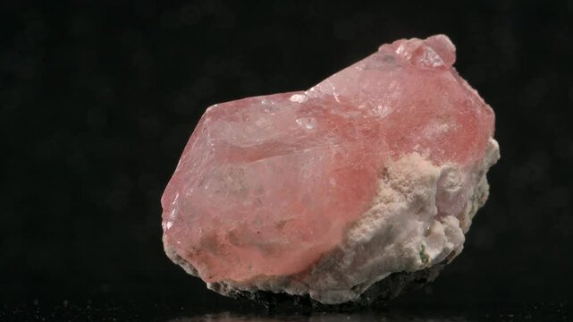 Pink Apophylite crystals on a rock matrix rotating slowly against a black background