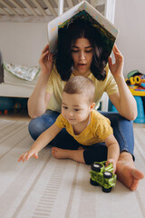 Mother and her two year old son playing in a children room, symbolizing motherhood and care