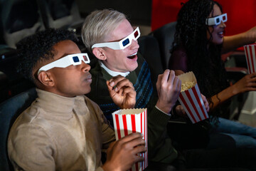 Friends watching 3d movie and eating popcorn in cinema