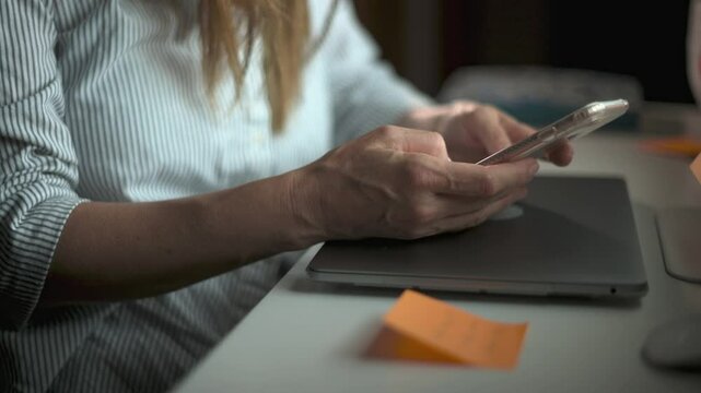Crop woman using smartphone in office