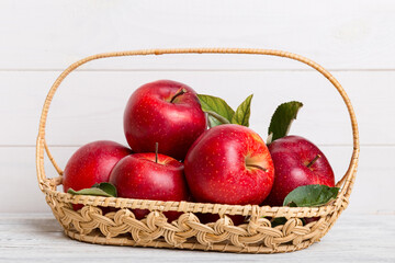 Ripe garden apple fruits with leaves in basket on wooden table. Top view flat lay with copy space