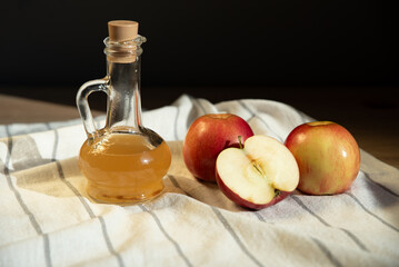 Apple cider vinegar in a jar and apples on the table