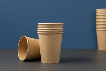 Disposable beige paper cups on a gray against blue closeup, mockup. No plastic lifestyle