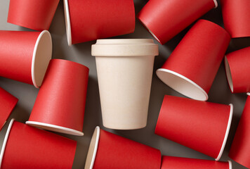 New red paper cups and beige reusable bamboo coffee cup on a gray top view, mockup