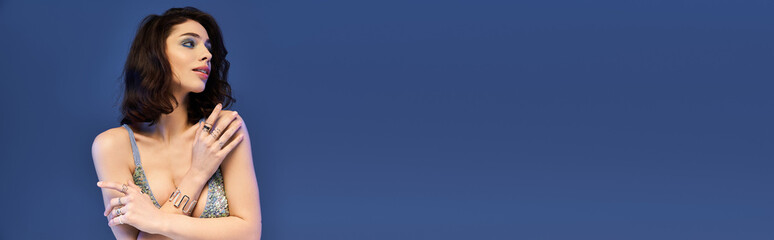 Young beautiful woman showcases summer fashion against bold blue background in striking pose