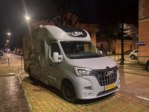 Modern grey Renault Master STX camper van parked on a brick paved parking strip on a residential street illuminated by streetlights at night, offering comfortable travel and accommodation