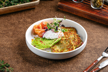 Breakfast with poached eggs zucchini pancakes salmon and avocado