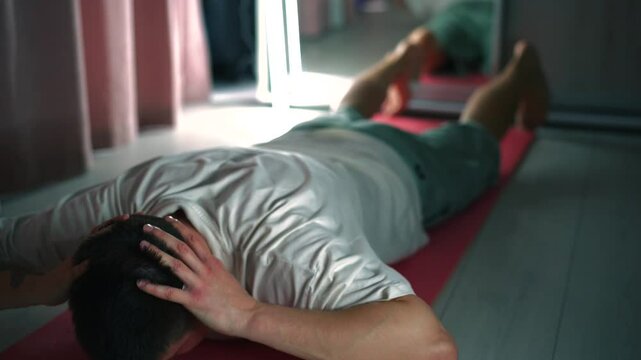 Un joven hace ejercicio sobre una colchoneta de ejercicios de color rosa.
Ejercicios deportivos.
Un hombre haciendo ejercicios de calentamiento en un gimnasio.