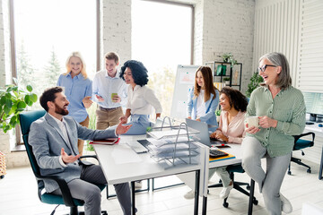 Group of diverse coworkers brainstorming ideas in a modern office with large windows, multi-age